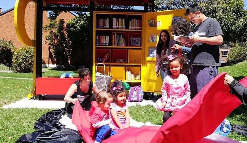 Varios niños y un adulto jugando y leyendo en un Paradero Paralibro