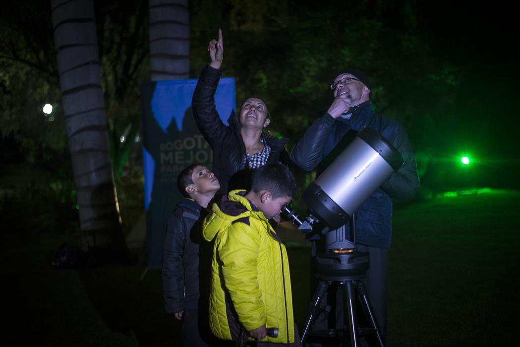 Un niño y dos adultos observando las estrellas por medio de un telescopio 