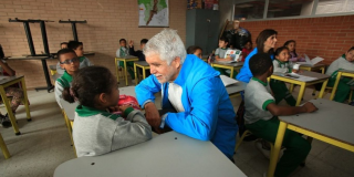 El Alcalde Enrique Peñalosa hablando con una niña en un salón de clases