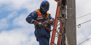 Imagen de un técnico de ENEL realizando mantenimiento en un poste de luz.