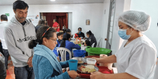 Imagen de una mujer recibiendo la bandeja del almuerzo