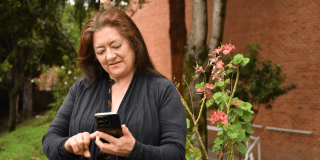 Imagen de frente de una señora viendo un celular