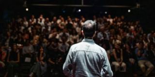 Foto de un hombre realizando una presentación ante un público en un audotorio.