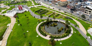 Vista aérea parque urbano de Bogotá con lago circular senderos áreas verdes y viviendas