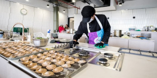 Persona prepara empanadas en aula culinaria del CEFE Cometas de Suba con estufas, bandejas y utensilios educativos