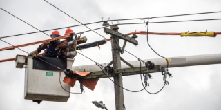 Imagen de dos técnicos de ENEL realizando trabajos de mantenimiento en un poste de energía.