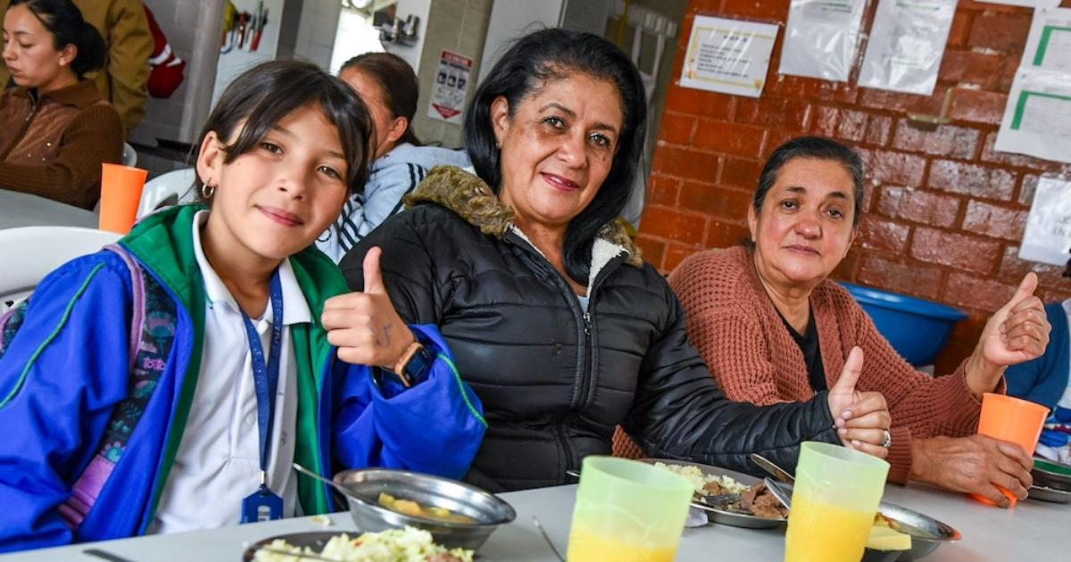 Imagen de una niña y dos señores comiendo un almuerzo en el nuevo comedor comunitario de Bosa