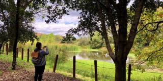 Lorena Posada tomando una fotografía con su celular al humedal.