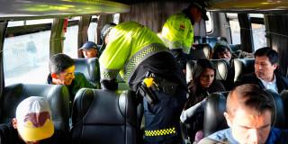 En la foto hay unos policías inspeccionando y requisando a los pasajeros de un bus intermunicipal