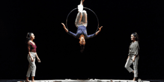 Imagen de un escenario donde pende un malabarista colgado en una circunferencia