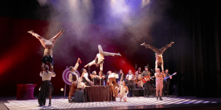 Imagen de la obra en el escenario donde se aprecian varios artistas haciendo sus malabares.