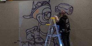 Foto que muestra un artista pintando una imagen en una pared