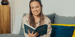 Imagen de mujer joven sentada con un libro en la mano