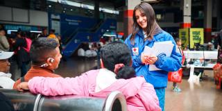 Una mujer de la Cruz Roja ofreciendo atención a una pareja migrante
