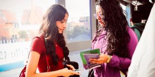 Una mujer que pertenece a la Secretaría de la Mujer le está mostrando un folleto a otra mujer