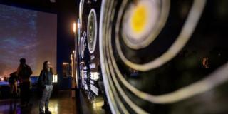 Imagen de personas observando exposición Máquinas para atrapar cometas y meteoritos
