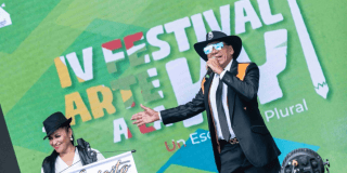 Imagen de cantante en tarima, de fondo se ve información del festival