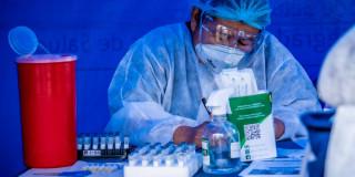 Foto que muestra una enfermera con un tapabocas puesto y escribiendo en un papel