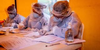 Foto que muestra enfermeras con un tapabocas puesto y escribiendo en un papel